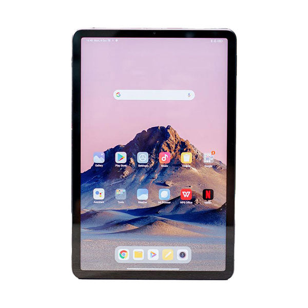 A black tablet with a large screen displaying a mountain wallpaper and various app icons, including YouTube, Netflix, and TikTok, on a pink background.