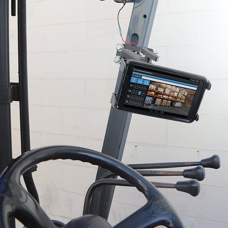 The Slim-Grip® Tablet Holder with Forklift Front Guard Mount and 10.25 Metal Arm holds a tablet on a forklift, showing inventory data and pallet images in a warehouse, with the steering wheel and control levers visible in front.