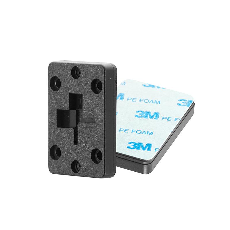 The 2-Way Single T-Slot Pattern to 4-Hole AMPS Adapter includes a black plastic AMPS mount with a cross-shaped cutout and multiple holes, plus an adhesive plate featuring white 3M PE foam backing.