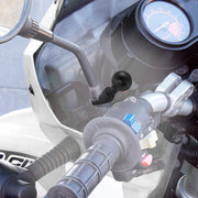 Close-up of a motorcycle handlebar highlighting the throttle grip, switches, part of the speedometer, and a rearview mirror fitted with the 25mm Ball to 9mm Angled Bolt Head Adapter near the rider’s right hand.