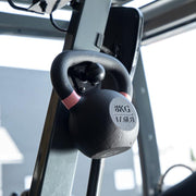 Close-up of an 88mm Heavy-Duty Magnetic Base with a 4-Hole AMPS pattern and screw bolts, mounted on a gym rack with blurred equipment and windows in the background.