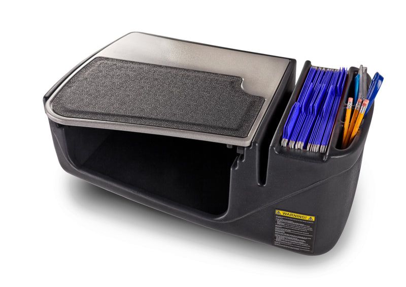 The AutoExec GripMaster Efficiency Car Desk by Arkon Mounts features a black design with a textured lid, a compartment for files or folders, and side slots for pens and pencils—ideal as a passenger seat desk or mobile workstation. A yellow warning label is visible on the front.