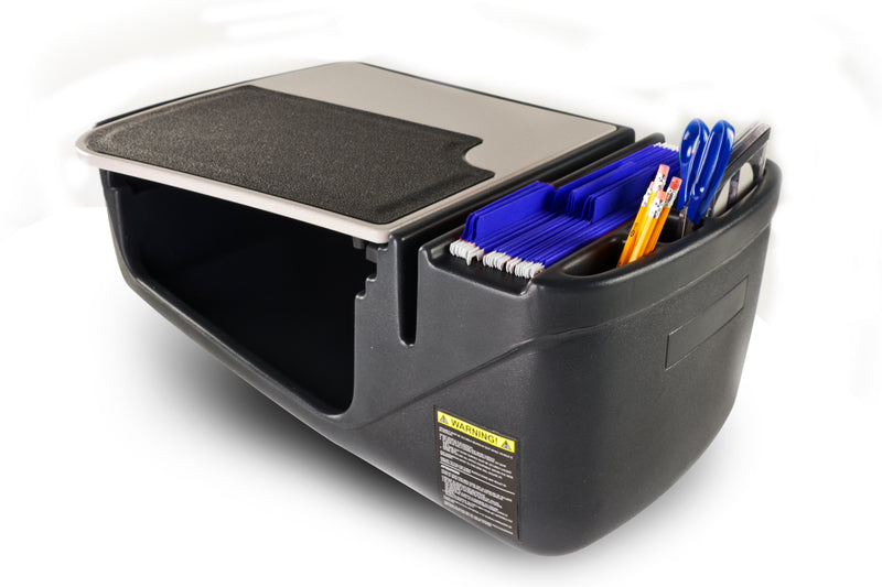 The Arkon Mounts AutoExec GripMaster Efficiency Car Desk is a black plastic desk organizer featuring slots for folders, pens, and scissors, along with a flat surface on top. Designed as a mobile workstation or passenger seat desk, it offers open compartments and has a warning label on the front side. Set against a white background.