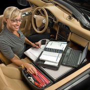A woman uses her laptop, planner, calculator, and office supplies—neatly organized on the Arkon Mounts AutoExec GripMaster Car Desk—to create a mobile workstation in her parked car.