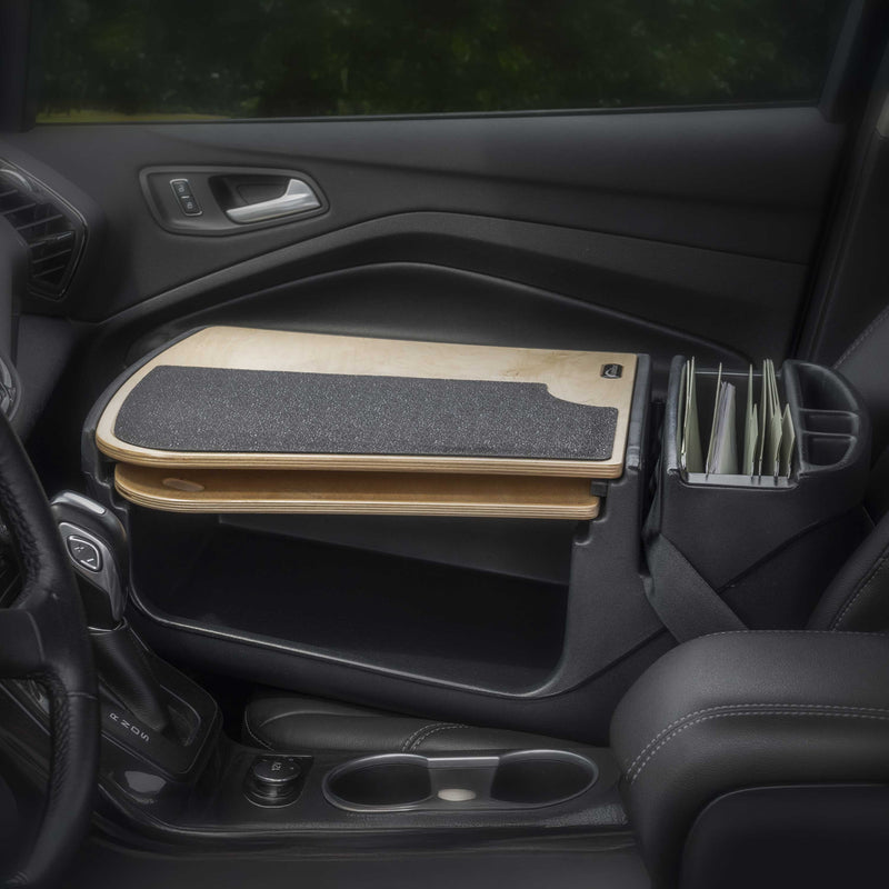 An Arkon Mounts AutoExec GripMaster Car Desk with a black textured wooden surface is installed over the passenger seat, serving as a mobile workstation. Next to it, near the gear shifter and cup holders, is a vertical organizer with folders.