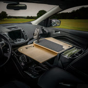 The car interior is transformed into a functional mobile office workstation with the AutoExec GripMaster Car Desk featuring a Mega Grip™ Drill-Base Mount, securely positioned over the passenger seat to hold a clipboard, mouse pad, files, and phone—set against the scenic backdrop visible through the windows.