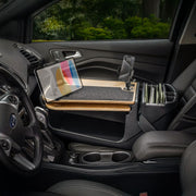 A parked car’s passenger seat is equipped with the AutoExec GripMaster Car Desk, featuring Mega Grip™ and Slim-Grip® Ultra Pro Drill-Base Mounts for secure placement of a tablet and smartphone, along with folders and other office essentials—transforming the vehicle into an efficient mobile workstation. Through the window, lush green trees provide a soothing background to this well-organized workspace on wheels.