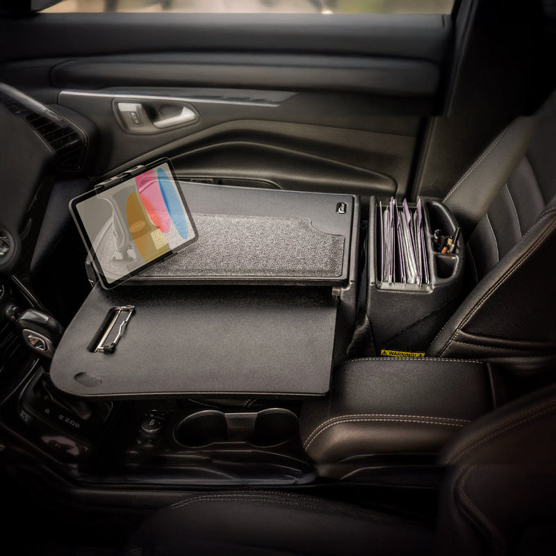 A car’s front passenger seat holds an Arkon Mounts AutoExec GripMaster Car Desk with Slim-Grip® Ultra Pro Drill-Base Mount, featuring a tablet mount, clipboard, and folder organizer to transform the space into a versatile mobile workstation.