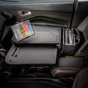 A car interior featuring the AutoExec GripMaster Car Desk with Slim-Grip® Ultra Pro Multi-Angle Mount by Arkon Mounts, equipped with a built-in tablet holder, clipboard, folders, and office supplies—perfectly illustrating a fully functional mobile office set up in the front passenger seat.