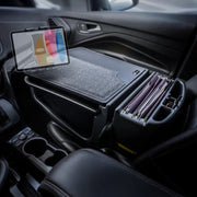The Arkon Mounts AutoExec GripMaster Car Desk with Slim-Grip® Ultra Pro Multi-Angle Mount is installed on the passenger seat, transforming the car into a convenient mobile office workspace with built-in file folders, a tablet holder, and storage compartments.