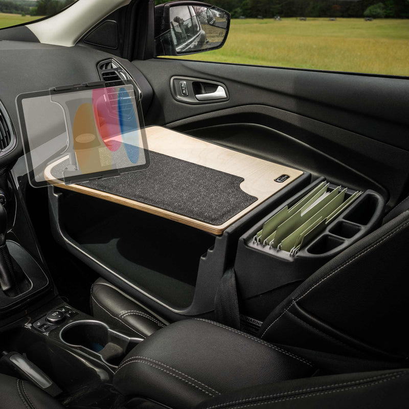 A GripMaster Efficiency Car Desk with Slim-Grip® Ultra Pro Drill-Base Mount by Arkon Mounts is set up in the front passenger seat, featuring a wooden desk surface, a cushioned mat, organized file folders, and a tablet securely held in its dedicated holder—transforming the car into a convenient mobile office workspace.