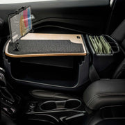 A car interior features the AutoExec GripMaster Efficiency Car Desk, equipped with a LockVise® Locking Tablet Holder and multi-angle mount, a felt-covered work surface, and organized file folders beside the passenger seat. This mobile workstation fits securely in the passenger footwell.
