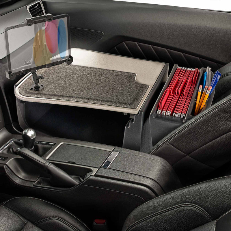 Sure! Here is the revised sentence using the provided product data: Car interior with a mounted AutoExec GripMaster Efficiency Car Desk featuring a LockVise® Locking Tablet Holder and Multi-Angle Mount, designed to hold a tablet, folders, and pens between the front seats. The desk covers the center console and extends to the passenger side, offering added security for your device while on the go.
