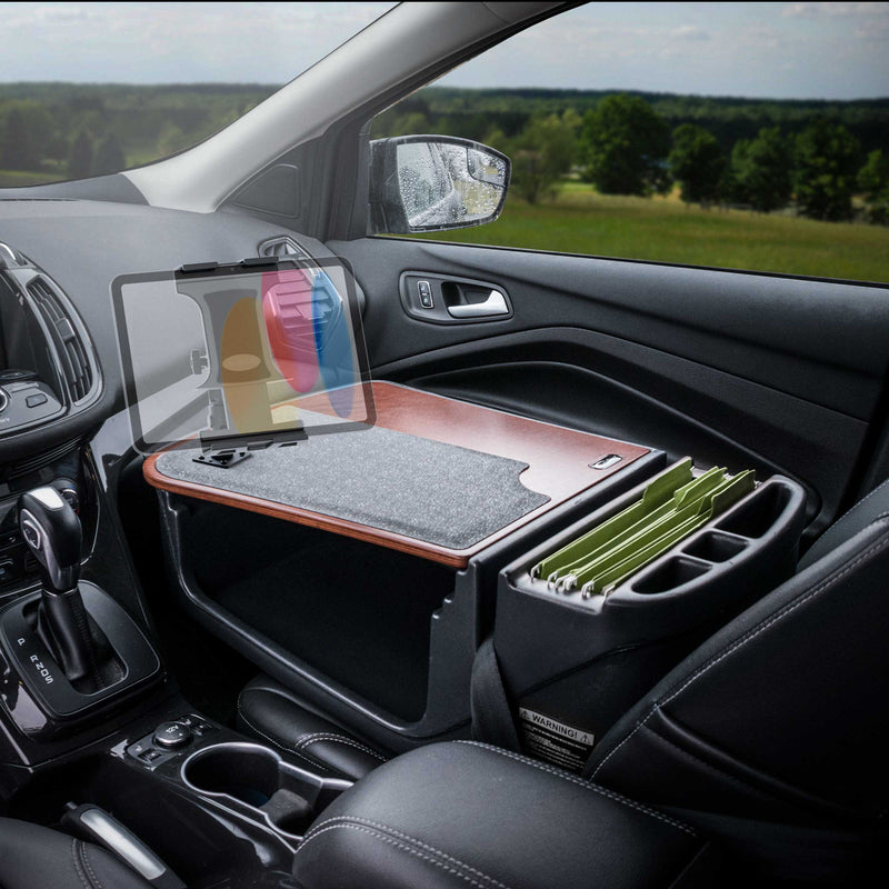 The Arkon Mounts AutoExec GripMaster Efficiency Car Desk with Slim-Grip® Ultra Pro Multi-Angle Mount transforms your car’s passenger seat into a functional mobile office, showcasing a sturdy desk setup with room for your laptop, organized files in the folder organizer, and an adjustable mount—all enhanced by the view of a green landscape through the window.