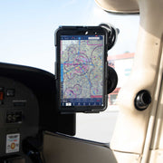 A SkyHold™ Windshield Dual Suction Tablet Mount secures a tablet showing an aviation navigation chart in the cockpit of a small aircraft, next to the control panel and window, with sunlight streaming into the interior.
