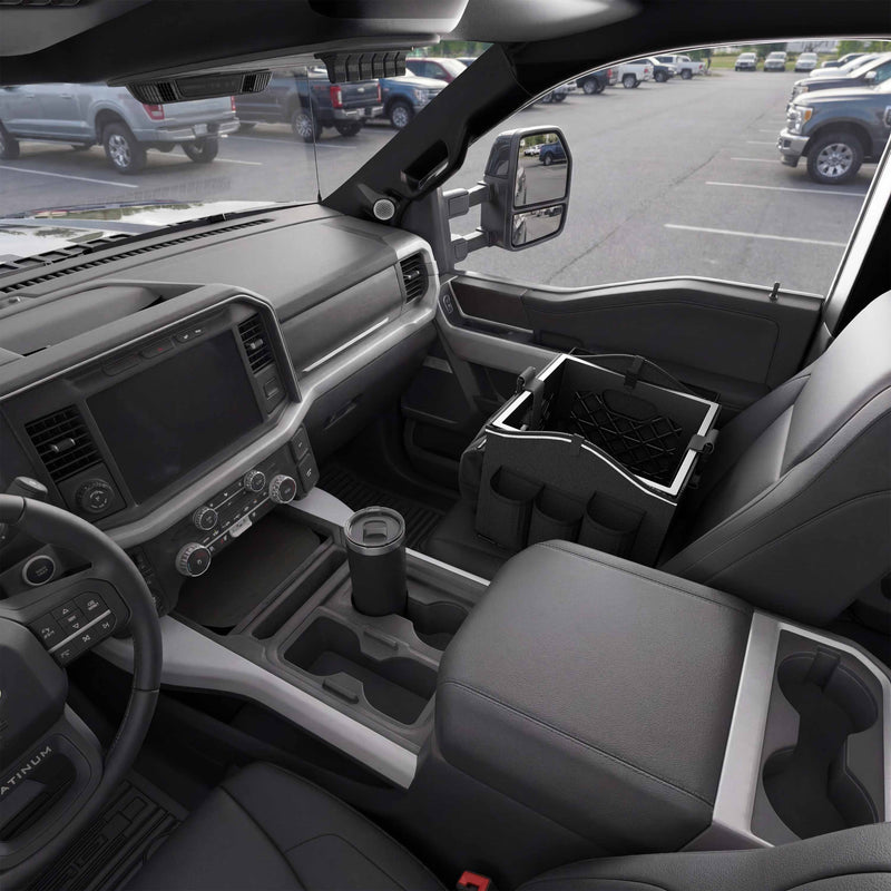 The interior of a parked pickup truck shows the front seats, dashboard, steering wheel, and a Portable Crate Workstation with Apron Organizer – Choose Your Mounting Setup placed on the passenger seat, offering convenient storage and versatile device mounting options for those using the vehicle as a mobile workstation.