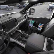 Inside a parked pickup truck, a Portable Crate Workstation with Apron Organizer—set up as a mobile workstation—securely holds both a tablet and a phone in the center console, while the windows reveal the parking lot and surrounding vehicles.