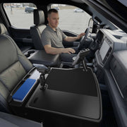 A man sits in the driver’s seat of a parked truck, working at an AutoExec GripMaster Efficiency Car Desk equipped with Mega Grip™ and Slim-Grip® Ultra Pro Drill-Base Mounts, where he organizes files and uses a securely mounted tablet at his center console workstation.