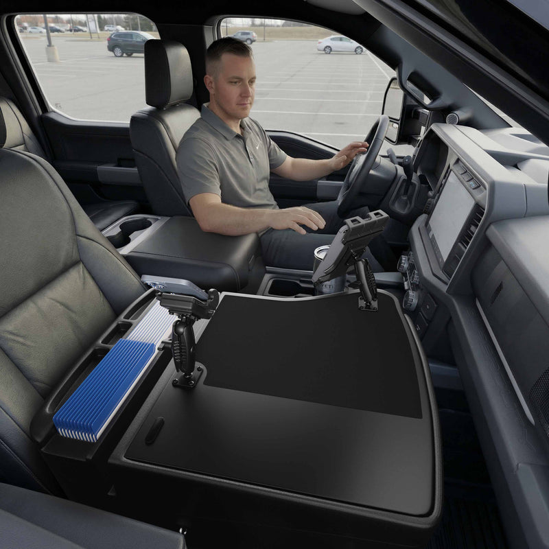 A man sits in the driver’s seat of a parked truck, working at an AutoExec GripMaster Efficiency Car Desk equipped with Mega Grip™ and Slim-Grip® Ultra Pro Drill-Base Mounts, where he organizes files and uses a securely mounted tablet at his center console workstation.