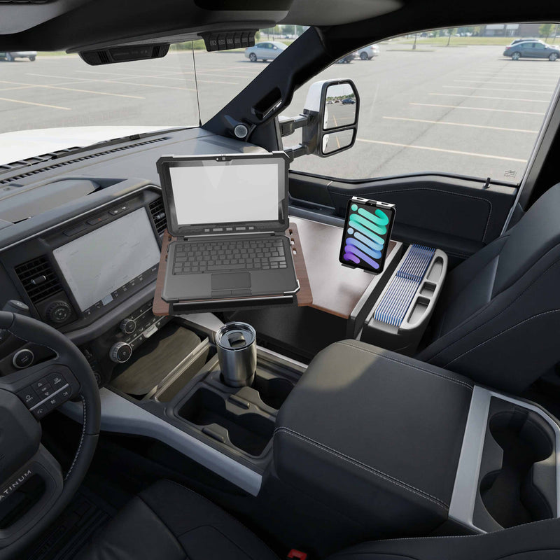 An AutoExec Reach Front Seat Car Desk by Arkon Mounts, featuring a Slim-Grip® Ultra Pro Multi-Angle Mount, is set up in the front seat of a truck parked in an empty lot, holding a laptop, smartphone, and travel mug to create an efficient mobile workstation.