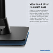 Close-up of the Desk Stand with 29 Height Adjustable Arm for MEVO, Cameras featuring a sturdy flat base on a blue pad. Text highlights its vibration and jitter resistance. Arkon Mounts logo appears at the bottom right.