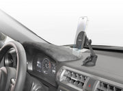 A smartphone is mounted on the Magnetic Phone Holder with Sticky Suction Mount—MagSafe Compatible—attached to the car dashboard near the steering wheel, with the vehicle’s digital instrument cluster and air vents visible.