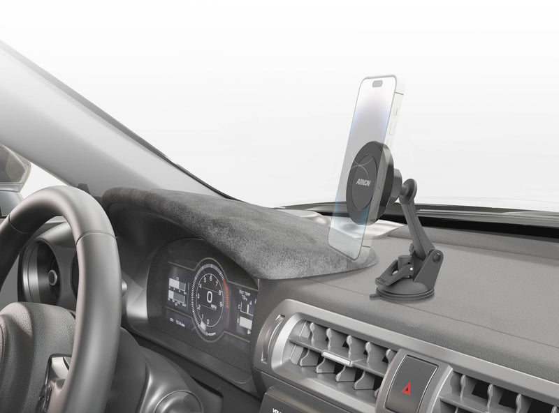 A smartphone is mounted on the Magnetic Phone Holder with Sticky Suction Mount—MagSafe Compatible—attached to the car dashboard near the steering wheel, with the vehicle’s digital instrument cluster and air vents visible.