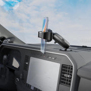The RoadVise® Ultra Pro Phone Holder 5” AMPS Drill-Base Mount is securely attached to a car dashboard above the touchscreen display and air vents, with a smartphone mounted in place and a bright sky visible through the windshield.