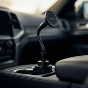 A Cup Holder Phone Mount with Gooseneck and 17mm Ball is installed in a car’s cup holder, showcasing its flexible neck and round base, with the car’s interior visible in the background. This adjustable mounting solution offers convenient access to your device while driving.