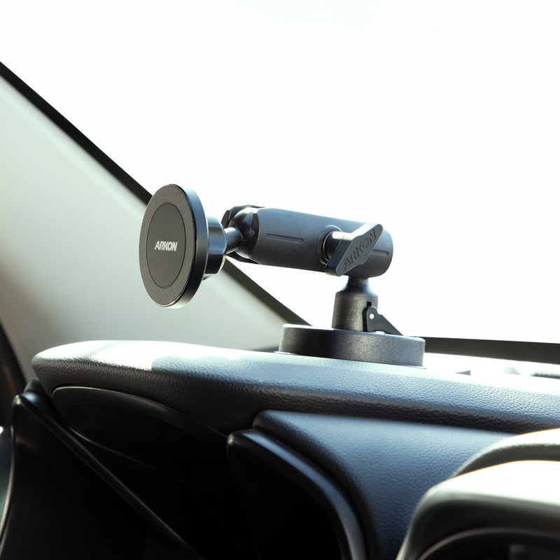 A Magnetic Phone Holder with Suction Mount (MagSafe Compatible) is attached to a dashboard near the windshield, ready to secure your device. The car’s interior and part of the windshield are visible in the background.