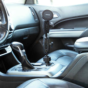 An Arkon Mounts Robust® Dual Shaft Cup Holder Mount with Magnetic Phone Holder (25mm, MagSafe compatible) is installed in the car’s center console cup holder next to the gear shift, with black leather seats and a modern dashboard in view.
