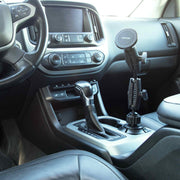 A Robust® Dual Shaft Cup Holder Mount with Magnetic Phone Holder (25mm, MagSafe Compatible) by Arkon Mounts is installed in the car’s center console cup holder near the gear shift. The dashboard, steering wheel, and climate controls are also visible.