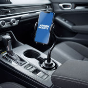 A Cup Holder Phone Mount with Gooseneck and 17mm Ball is secured next to the gear shift in a modern car interior, providing an adjustable mounting solution for convenient hands-free use.