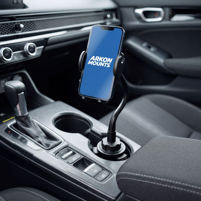 A Cup Holder Phone Mount with Gooseneck and 17mm Ball is secured next to the gear shift in a modern car interior, providing an adjustable mounting solution for convenient hands-free use.