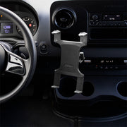 A black car interior with a steering wheel, dashboard, and an empty Slim-Grip® Tablet Holder with Double Socket Swivel Arm and Drill-Base Mount installed near the center console. The radio, air controls, and cup holders are also visible.