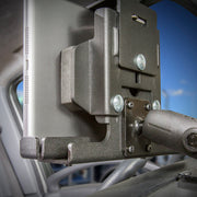 Close-up of the LockVise™ Metal Locking Tablet Mount Bundle with USB and Quick Hardwire Adapter securely holding a tablet next to the driver’s seat inside a vehicle, with parts of the car interior and a window visible in the background.