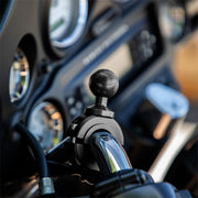 Close-up of a motorcycle handlebar featuring the Aluminum Motorcycle Handlebar Mount - 25mm (1 inch) Compatible, with dashboard instruments and gauges blurred in the background.