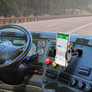 A Drill-Base Mega Grip™ Phone Mount secures a smartphone with navigation on a truck dashboard; the adjustable arm holds the phone near the steering wheel and control panel, with a highway scene visible through the windshield.