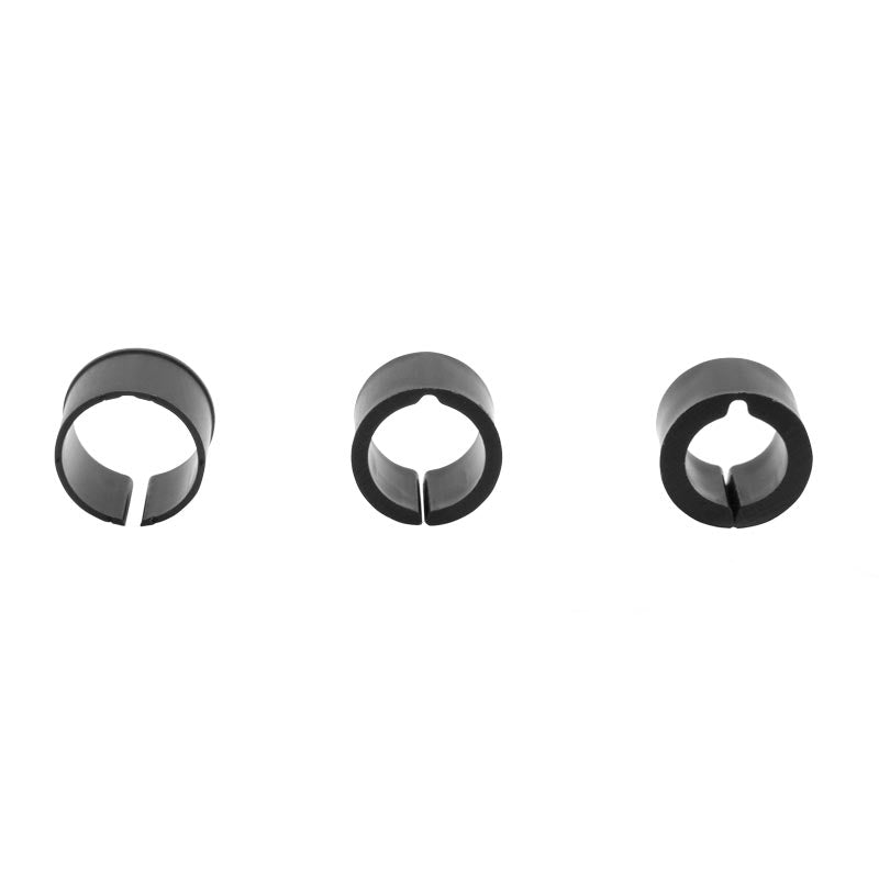 Three black circular clips with open slits, evenly spaced on a white background—the Handlebar Spacer Kit is perfect for use as handlebar adapter rings to customize your bike setup.