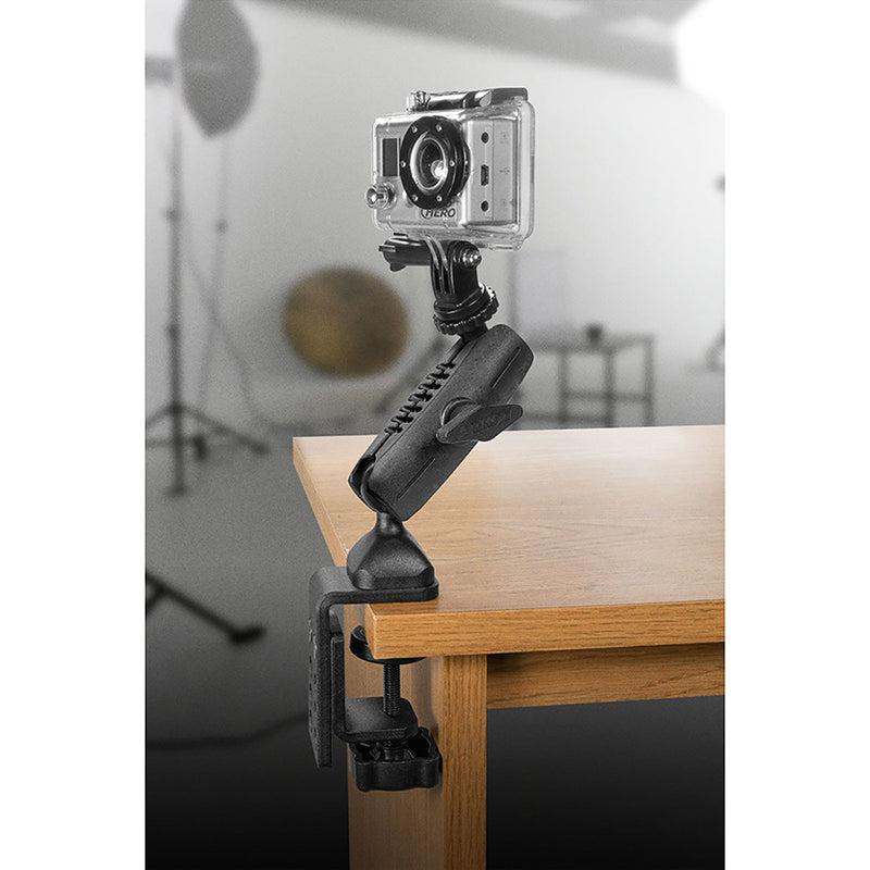 A GoPro HERO Action Camera is securely attached to a wooden table in a photography studio using the Heavy-Duty Adjustable Clamp Mount—an ideal live streaming accessory.