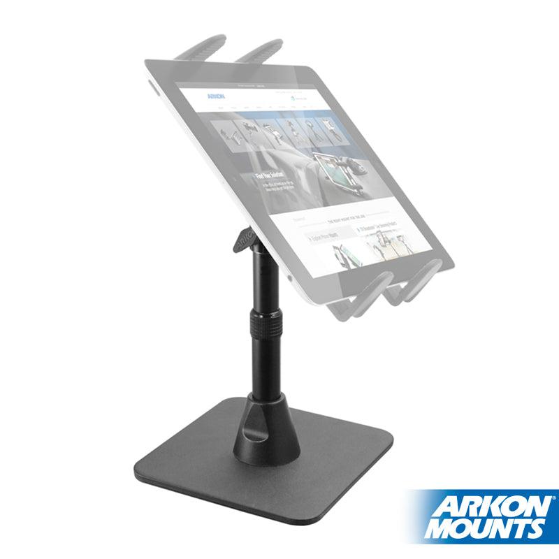 The Heavy-Duty Pedestal Stand with Weighted Base and Telescoping Arm – 4-Hole AMPS Compatible securely holds a tablet at an angle, displaying a website, with the Arkon Mounts logo shown in the bottom right corner.