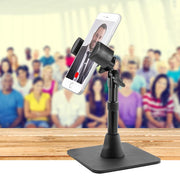 A Heavy-Duty RoadVise® Phone Stand holds a smartphone showing a man in a suit on a video call, while content creators gather in the brightly lit background.
