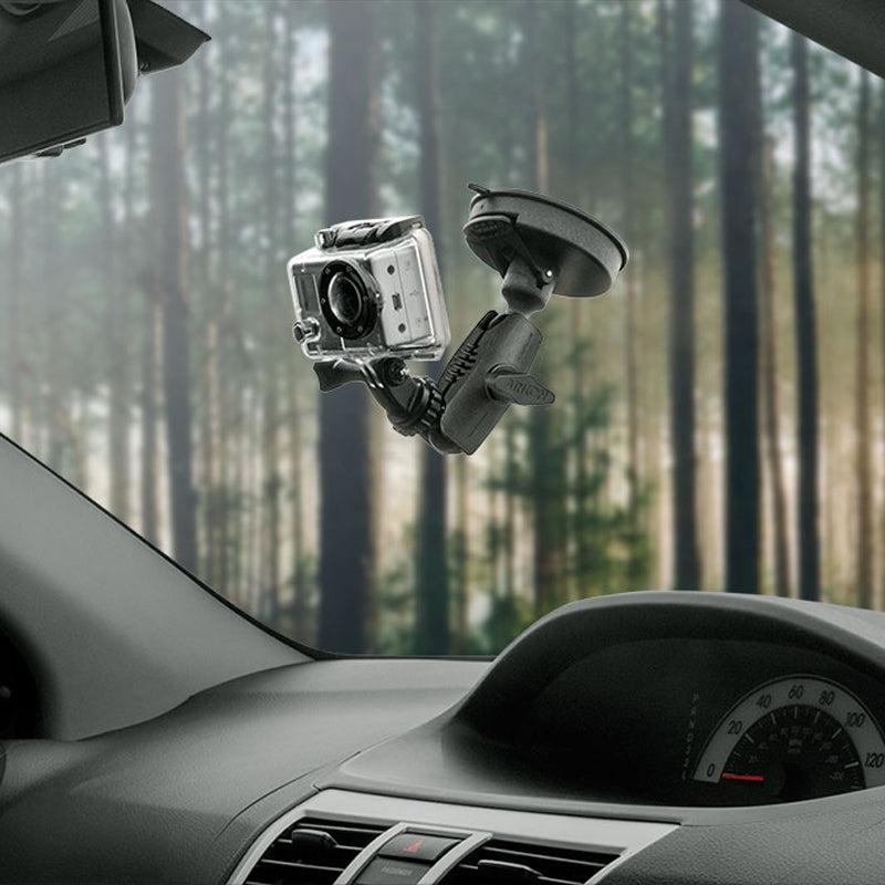 A GoPro HERO Action Camera, attached to a car windshield with the Heavy-Duty Sticky Suction Mount, captures a serene forest scene visible through the window in the background.