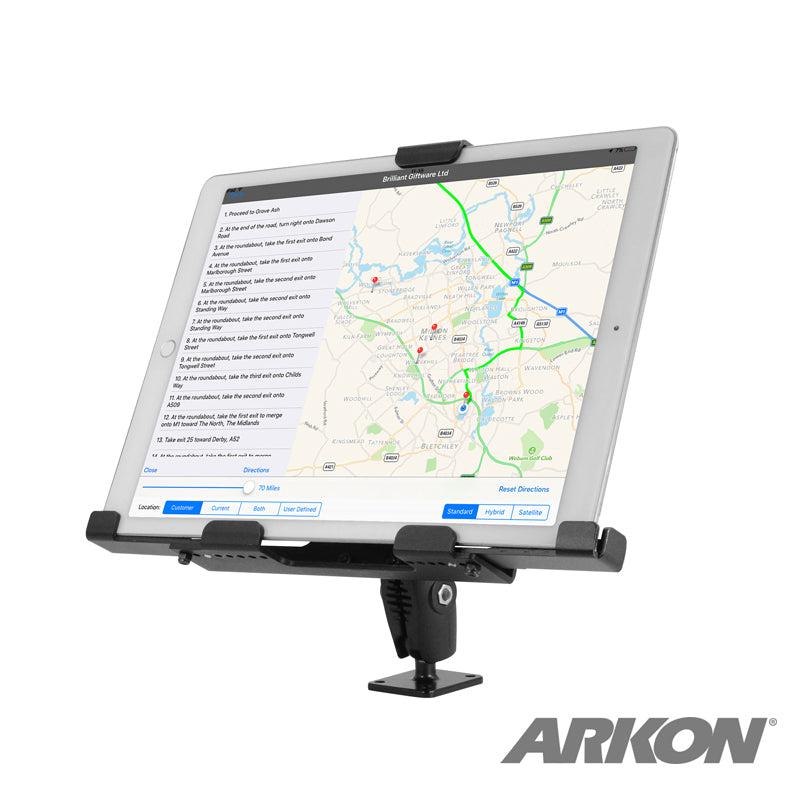 The LockVise™ Metal XL Locking Tablet Holder with Drill Base Mount in sleek black securely holds a tablet displaying map directions. ELD compliant and adjustable, it’s attached to a flat surface with the ARKON logo in the bottom right corner.