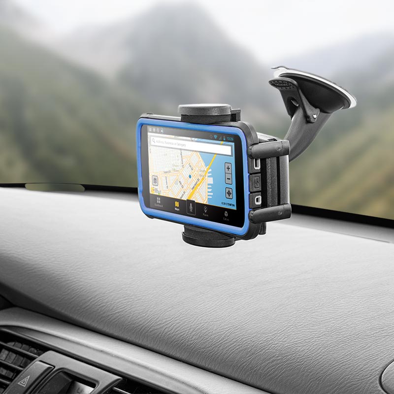 A Mega Grip™ Phone Holder with Windshield and Dash Car Mount securely holds a smartphone on the dashboard, displaying a GPS navigation map while the car is parked in a scenic mountainous area.