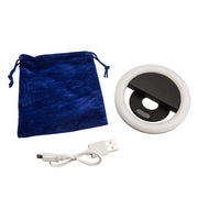 The Rechargeable Clip-On LED Ring Light, a white USB charging cable, and a blue velvet drawstring pouch are displayed on a white background.