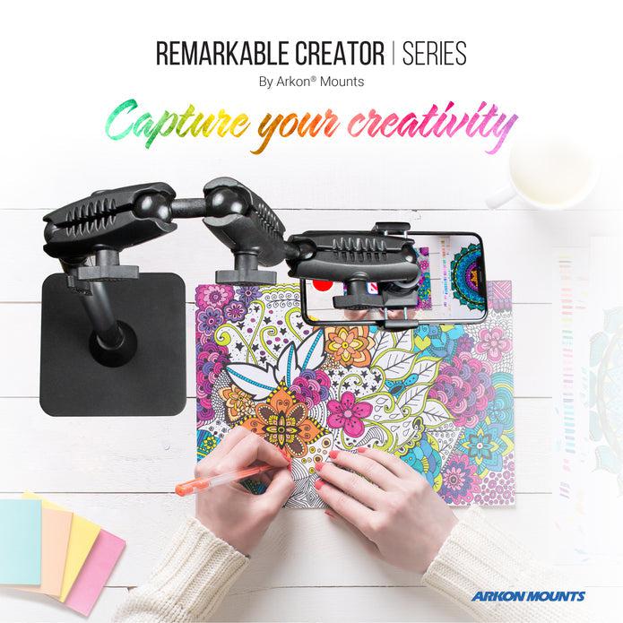 Someone colors a detailed floral design while recording with the Remarkable Creator™ Pro Mount. Text on screen: Remarkable Creator™ Pro Mount by Arkon Mounts. Capture your creativity. Stationery is scattered nearby.