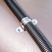 Close-up of a Replacement Metal Conduit for Seat Rail Mounts in black, attached to a textured light brown surface with a shiny metal clamp and two screws for vibration prevention.