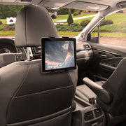 A Slim-Grip® Tablet Headrest Mount secures a tablet showing a fantasy scene to the back of a car’s front seat. The sleek black interior and suburban views outside make it the perfect rear seat entertainment solution.