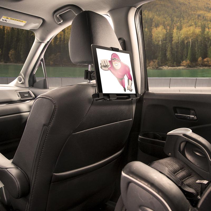 The LockVise™ Metal Locking Car Headrest Tablet Mount holds a tablet showing a pink cartoon character, keeping kids entertained. A childs car seat is in view, with scenic trees and mountains visible outside the window.